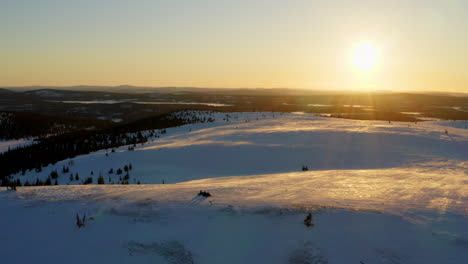 Aerial-view-across-stunning-sunrise-sunlit-Lapland-snowy-hills-and-valleys-landscape