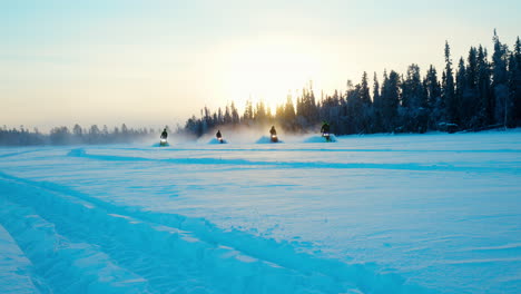 Team-of-snowmobile-riders-speeding-slow-motion-across-snowy-arctic-circle-woodland-trail
