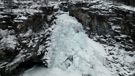 Aerial-view-of-frozen-waterfall-down-cliffs---cascading-water-visible-underneath