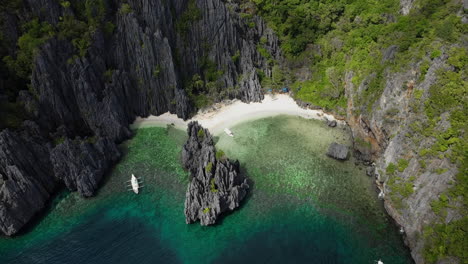 Boats-pull-ashore-on-an-isolated-beach-surrounded-by-steep-cliffs-on-tropical-island