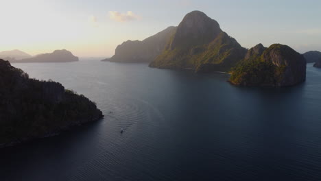 Aerial-view-as-sun-sets-on-ocean-horizon-with-steep-cliff-islands-in-Asia