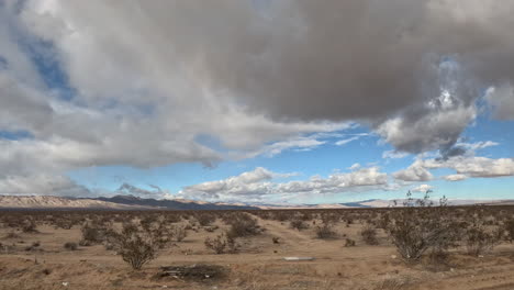 Die-Mojave-Wüstenlandschaft-Zieht-Vorbei,-Während-Wolken-Im-Treibenden-Hyperlapse-Aus-Der-Sicht-Eines-Autofahrers-Den-Himmel-überziehen