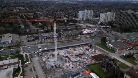Drone-shot-orbiting-around-a-construction-site-with-a-crane-in-a-suburban-neighbourhood,-Toronto,-Ontario,-Canada
