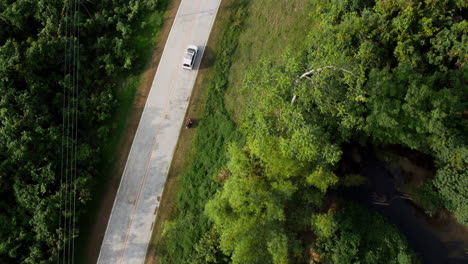 Drone-shot-following-a-car-driving-along-forestry-area