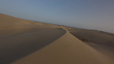 Aerial-fast-low-flight-over-sand-dunes-at-sunset