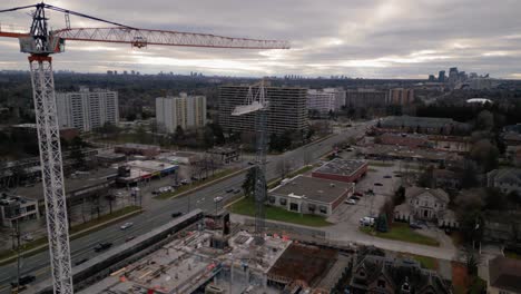 Drone-jib-shot-of-construction-site-with-a-crane-in-a-suburban-area,-flying-down-to-reveal-the-workers-inside