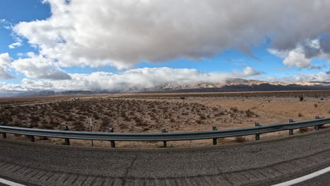 Conduciendo-A-Través-Del-Terreno-Accidentado-Del-Desierto-De-Mojave-En-Una-Carretera-Como-Se-Ve-Desde-La-Ventana-Del-Pasajero
