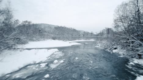 Luftaufnahme-Des-Zugefrorenen-Flusses-Und-Der-Hängebrücke-Am-Frostigen-Wintermorgen