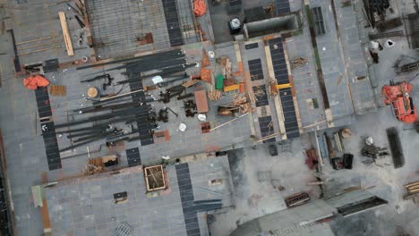 Drone-shot-flying-up-from-an-empty-construction-site,-bird's-eye-view