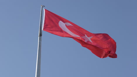 Cámara-Lenta,-Bandera-Nacional-De-Turquía-Ondeando-En-El-Poste-Bajo-Un-Cielo-Azul-Claro