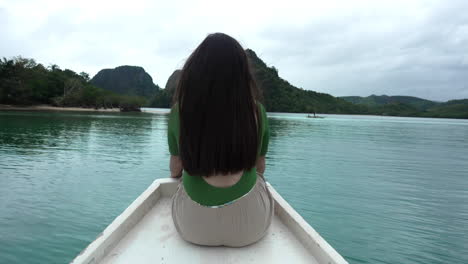 Woman-with-black-hair-sitting-on-front-of-moving-boat-in-calm-sea