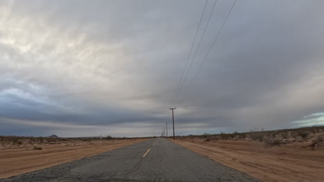 An-Einem-Bewölkten-Tag-Eine-Leere-Straße-In-Der-Mojave-Wüste-Hinunterfahren