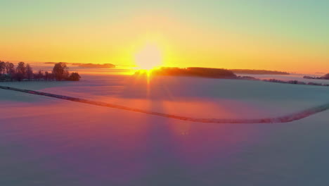 Orange-color-from-a-brilliant-golden-sunset-reflects-off-the-snow-in-a-winter-wonderland---aerial-flyover