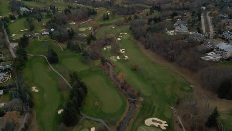 Aerial-drone-shot-flying-above-a-golf-course-and-revealing-a-city-horizon-in-Toronto,-Ontario,-Canada