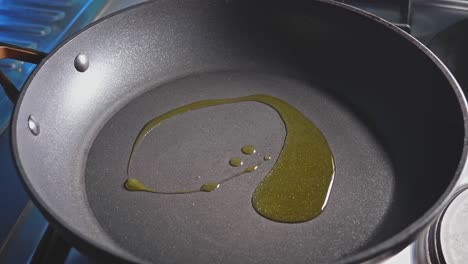 Pouring-olive-oil-in-a-pan-with-a-spoon,-close-up-view
