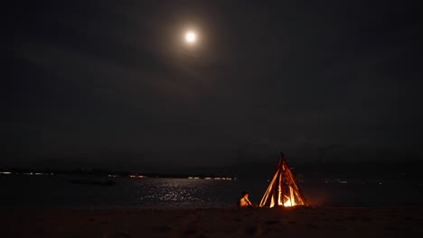 Bonfire-Burning-Under-Tropical-Full-Moon-Moonlight-on-Komodo-Beach,-Indonesia