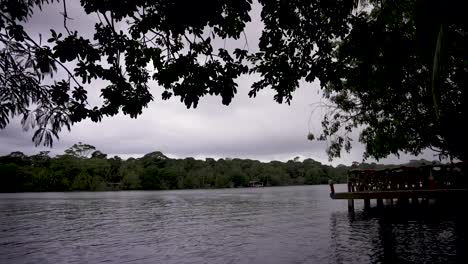 River-boat-dock-at-the-Tarcoles-river-in-Costa-Rica-with-tree-in-foreground,-Handheld-wide-shot