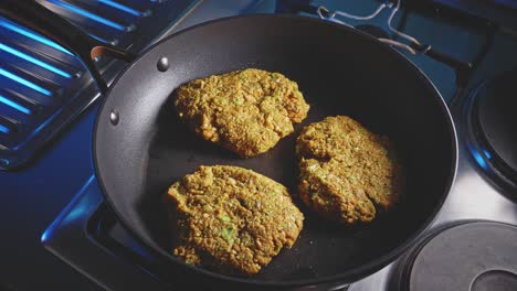 Man-flipping-veggie-patties-and-covering-the-non-stick-frying-pan-with-tempered-glass,-close-up-shot