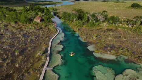 Aerial-view-of-people-kayaking-in-the-narrow-channel-of-Bacalar-rapids,-in-sunny-Mexico