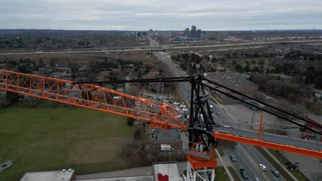 Drone-flies-by-a-construction-crane-revealing-a-city-in-the-horizon,-Toronto,-Ontario,-Canada