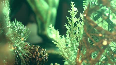 Close-up-of-a-plastic-tree-with-pinecones-for-Christmas-decorations,-illuminated-by-lights