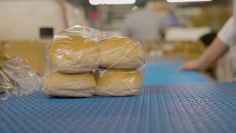 Brotbrötchen-In-Einer-Plastiktüte-Auf-Einem-Förderband,-Das-Von-Einem-Arbeiter-Abgeholt-Wird