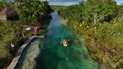 Aerial-view-following-people-canoeing-through-a-exotic,-jungle-channel,-in-Bacalar,-Mexico