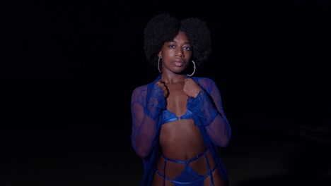 Young-woman-with-an-afro-and-sexy-blue-lingerie-on-the-beach-at-night