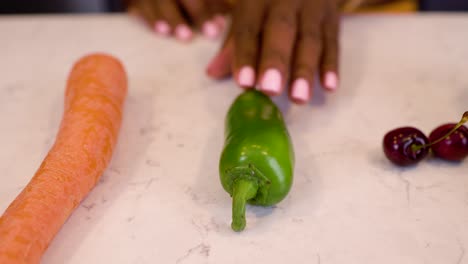 black-woman-hand-is-seductively-grabbing-green-pepper-vegetables-on-a-marble-kitchen-table