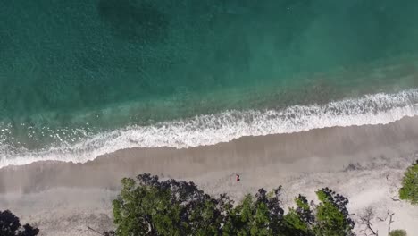 Aerial-view-of-a-girl-relaxing-on-a-paradisiacal-beach-in-Costa-Rica
