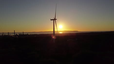 Establisher-static-shot-of-silhouetted-wind-turbine-turning-against-sunset