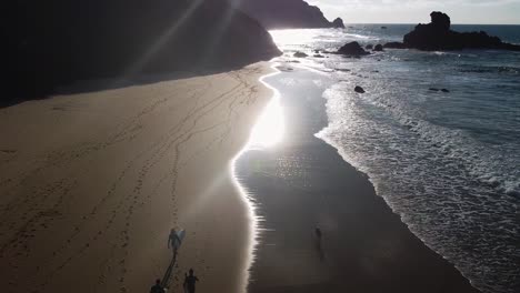 Eine-Gruppe-Von-Surfern-Und-Ein-Hund,-Die-Während-Des-Sonnenuntergangs-An-Der-Algarve,-Portugal,-Am-Strand-Spazieren-Gehen