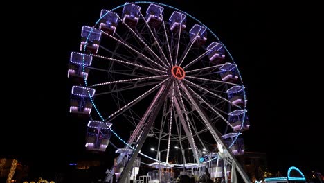 Colorful-ferries-wheel-with-neon-lights-rotating-on-city-square-on-holidays