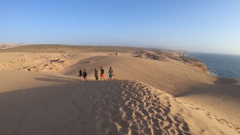 Excursionistas-Caminando-En-Las-Dunas-Del-Desierto-Marroquí