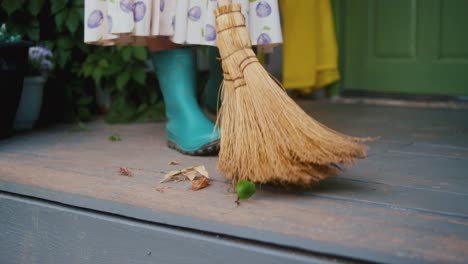 Woman-is-wearing-a-dress-with-rubber-boots-sweeping-the-floor