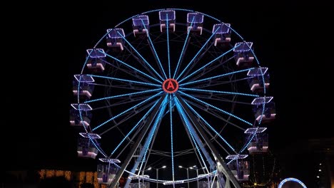 Ferries-wheel-illuminated-by-neon-colorful-lights-rotating-on-center-of-dark-sky-background
