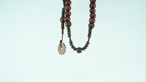 Eine-Hölzerne-Halskette-Mit-Einer-Asiatischen-Alten-Münze,-Makroaufnahme-Nahaufnahme-4k,-Weißer-Hintergrund