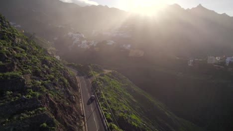 Aerial-view-of-car-driving-along-Taganana-village-at-sunset-in-Anaga-National-Park,-Tenerife