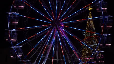 Ferries-wheel-and-New-Year-Tree-illuminated-by-colorful-lights-on-night-sky-background
