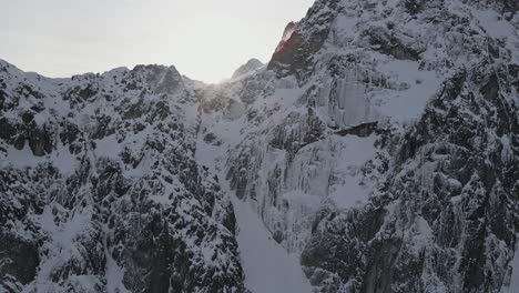 Drone-footage-of-a-sunrise-above-a-snowy-mountain-cliff