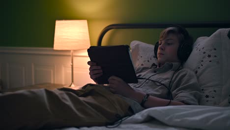 Boy-watching-a-video-on-his-ipad-laying-on-bed