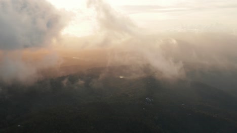 Luftaufnahme,-Die-Bei-Sonnenuntergang,-Sonnenaufgang-Durch-Leichte-Wolkenfetzen-In-Goldenem-Licht-Fliegt