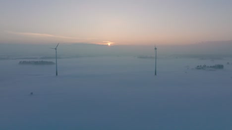 Luftbild-Von-Windkraftanlagen,-Die-Im-Windpark-Erneuerbare-Energie-Erzeugen,-Schneebedeckte-Landschaft-Mit-Nebel,-Sonniger-Winterabend-Mit-Goldenem-Stundenlicht,-Weites-Drohnenbild,-Das-Sich-Vorwärts-Bewegt