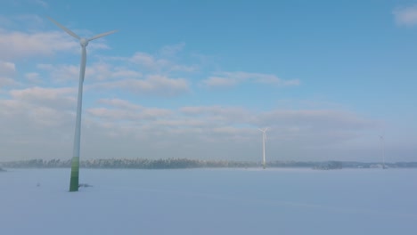 Vista-Aérea-De-Las-Turbinas-Eólicas-Que-Generan-Energía-Renovable-En-El-Parque-Eólico,-Paisaje-Rural-Lleno-De-Nieve-Con-Niebla,-Día-Soleado-De-Invierno,-Gran-Tiro-De-Drones-Avanzando