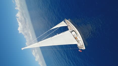 Drone-flying-around-luxury-white-Oyster-82-yacht-sailing-on-blue-ocean-waters-with-horizon-in-background
