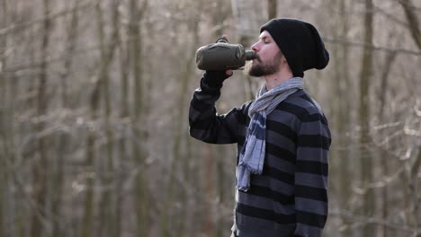 Portrait-of-male-hiker-drink-water-from-canteen-on-trip-in-forest-on-autumn-day