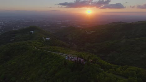 Scenic-sunset-aerial-arc-over-building-in-Santiago-Mountains,-Dominican-Republic