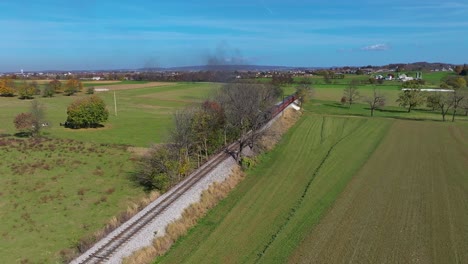 An-Aerial-View-of-a-Steam-Train-Traveling-Over-a-Small-Bridge-as-it-Travels-Thru-Country-Farmlands-on-a-Sunny-Fall-Day