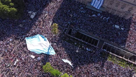Die-Anhänger-Der-Argentinischen-Fußballmannschaft-Feiern-Den-Sieg-Der-Weltmeisterschaft-In-Den-Straßen-Von-Buenos-Aires-Mit-Einer-Riesigen-Fahne-über-Ihren-Köpfen