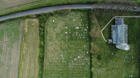 Topdown-Drohne-Aus-Der-Luft,-Die-An-Einem-Bewölkten-Tag-In-North-Norfolk,-Großbritannien,-über-Die-Alte-Mittelalterliche-Rundturmkirche-Aus-Dem-11.-Jahrhundert-Mit-Friedhof-Fliegt